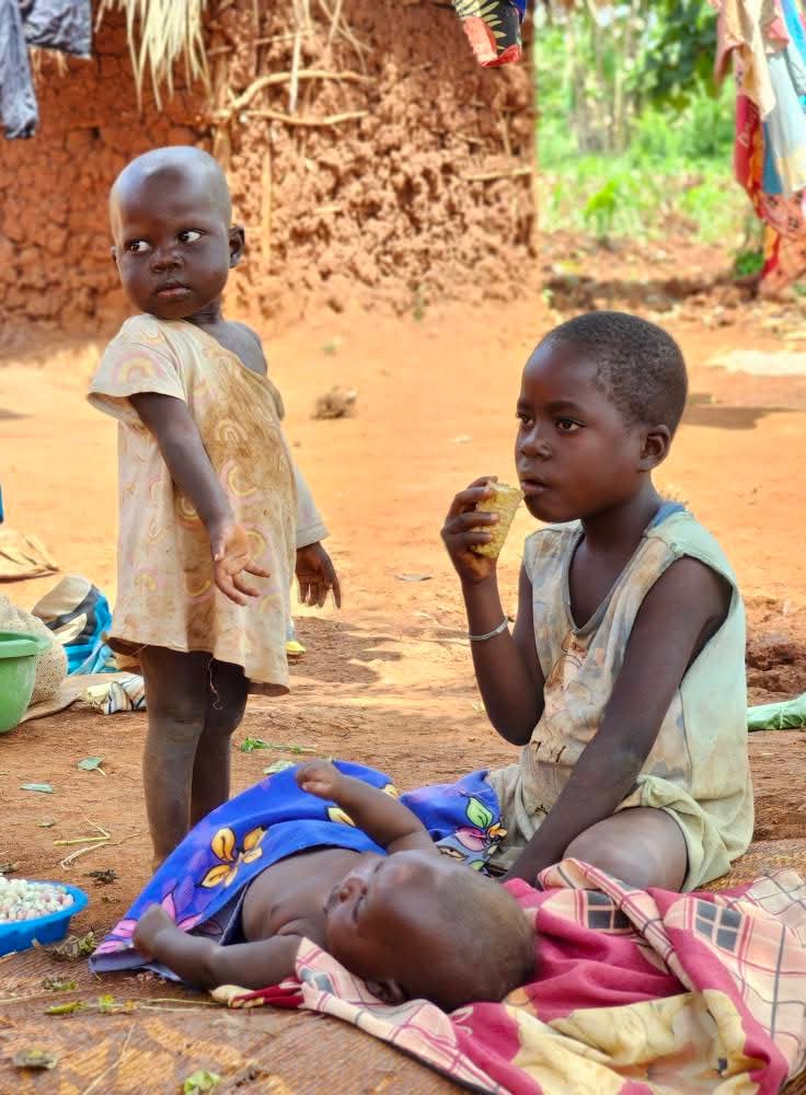 Siblings looking after each other and their baby sister in Eastern Uganda